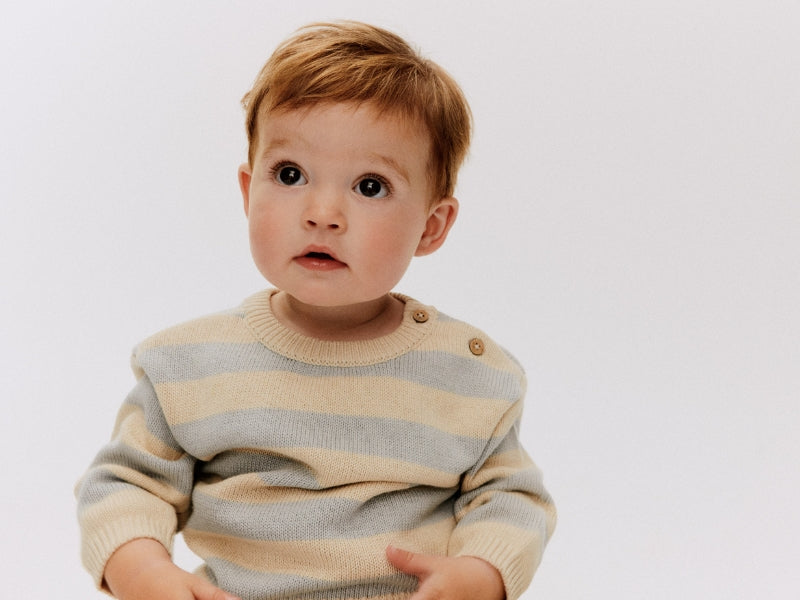 A baby wearing a blue striped sweater