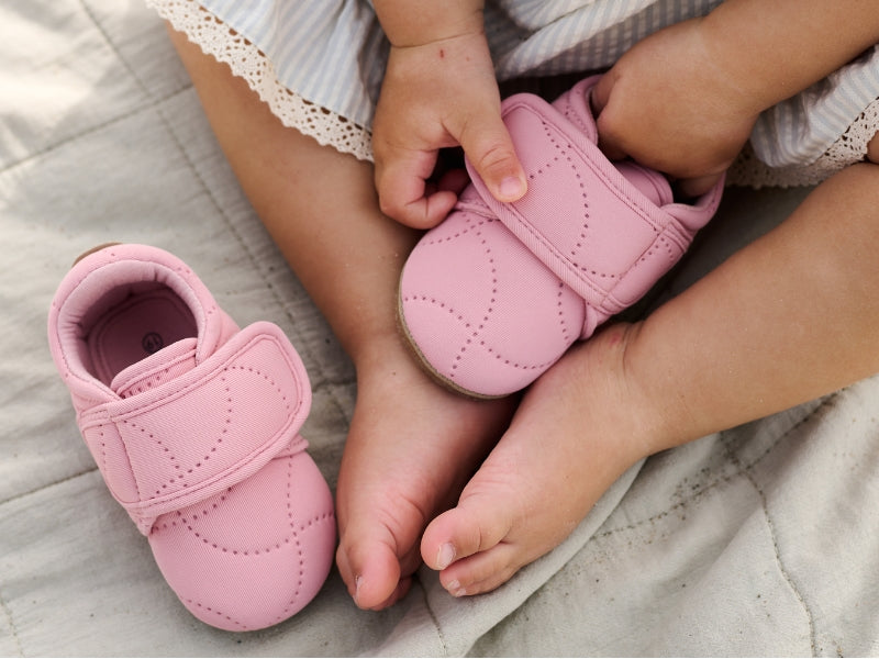 a pair of pink indoor shoes and a baby