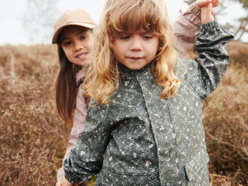 Two children in outdoor clothing standing in a natural setting.